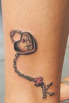 a tattoo on the leg of a woman with a key and heart attached to it