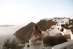 a woman in a wedding dress standing on the steps to a cliff overlooking the ocean