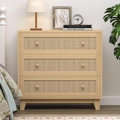 a bedroom scene with focus on the chest of drawers and a plant next to it