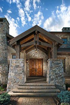 a stone house with a wooden door and steps leading up to the front entrance area