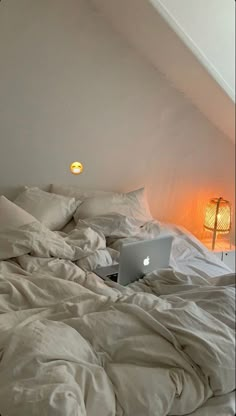 an open laptop computer sitting on top of a bed in a room with white sheets