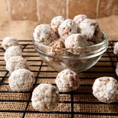 a glass bowl filled with snowball cookies on top of a table