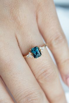 a woman's hand with a ring on it and a blue stone in the middle