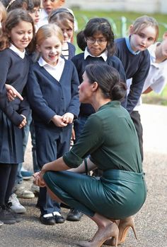 a woman kneeling down next to a group of children