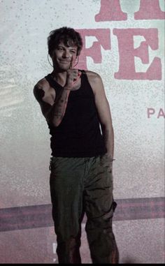 a man standing in front of a sign giving the peace sign with his hand and finger