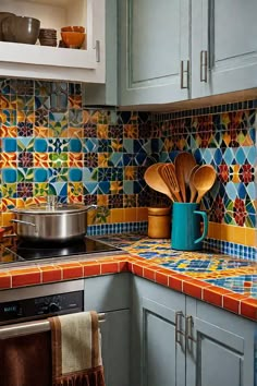 a kitchen with colorful tiles and wooden utensils on the counter top next to an oven