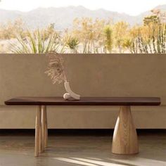 a wooden table sitting in front of a wall with mountains in the backgroud