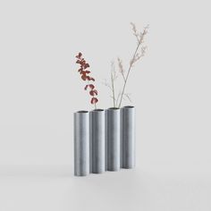 three metal vases with flowers in them on a white surface, one is empty