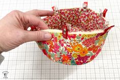 someone is making a flowered bag out of fabric