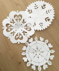 three pieces of paper cut out to look like snowflakes on a wooden table