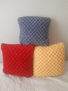 three knitted pillows sitting on top of a white bed next to eachother