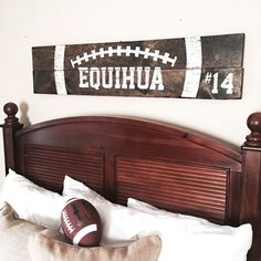 a bed with a wooden headboard and football sign above it