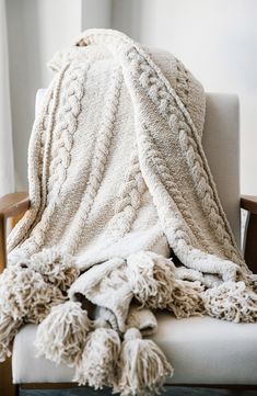 a white blanket sitting on top of a wooden chair