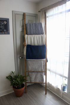 a ladder that has towels on top of it in front of a potted plant