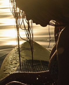 a woman sitting on top of a surfboard in the middle of water at sunset