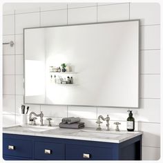 a bathroom vanity with two sinks and a large mirror above it, in front of a white tiled wall