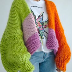 a woman wearing an orange, pink, and green knitted sweater with colorful sleeves