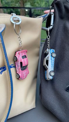 two purses with cars attached to them sitting next to each other