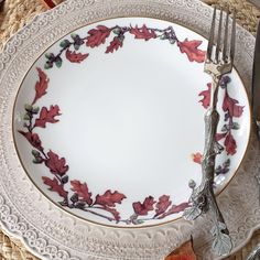 a white plate with red leaves on it next to silverware and utensils