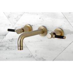 two brass faucets on a white marble wall