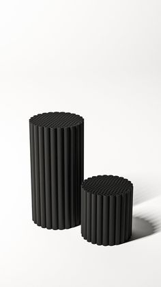 two black vases sitting next to each other on a white surface with shadows coming from them