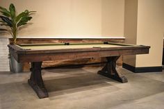 a pool table in a room with a potted plant