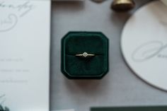 an engagement ring in a green velvet box on top of a table with other items