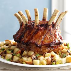 a large piece of meat on top of potatoes and other food items sitting on a white plate