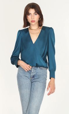 The perfect teal blouse features faux wrap front, long cuffed sleeves, a v-neckline with snap closure, a back yoke, and a slight hi-lo hem. Fully lined.  Long sleeve blouse  Sateen Cuffed Faux wrap Back yoke  Lined Self: 98% Polyester, 2% Spandex Lining: 100% Polyester Length: 19 12" Across shoulder: 14 5/8" Machine wa Teal Outfits, Wrap Front Top, Teal Blouse, Luxury Women Fashion, Mother Denim, Top Top, Hem Style, Business Casual Outfits, Work Attire