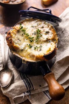 a pot pie with cheese and herbs in it on a napkin next to two spoons