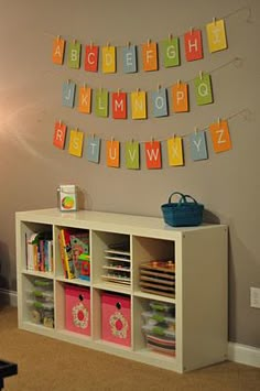 a child's playroom with toys and letters on the wall