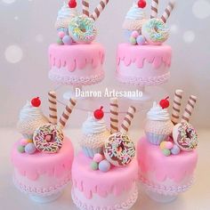 there are many small cakes with candy decorations on the top one is pink and has white frosting