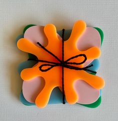 an orange and pink flower with black string on it's center, sitting on a white surface