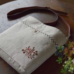 a purse sitting on top of a wooden table next to a bouquet of wildflowers