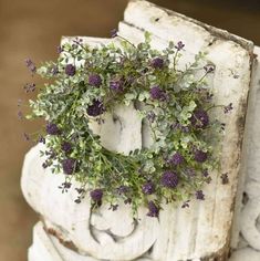 a wreath is placed on top of an old white box with purple flowers in it