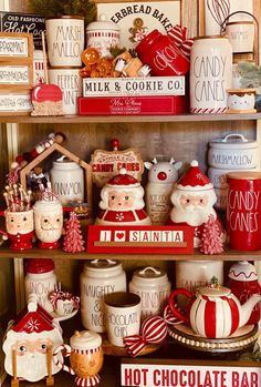 a shelf filled with lots of christmas themed dishes and candy bars on top of wooden shelves