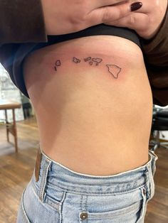 a woman's lower back tattoo with the world map on her left side ribcage