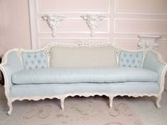 a blue couch sitting in front of a pink wall