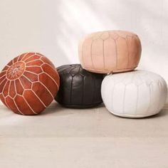 four different colored poufles sitting on top of each other in front of a white wall