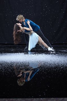 a man and woman are dancing in the rain with water splashing on their faces