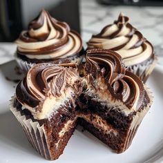 three chocolate cupcakes on a plate with one cut in half