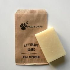 a bar of handmade soap next to a brown bag with paw soaps on it