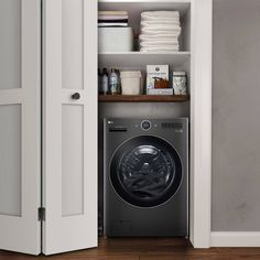 a washer sitting inside of a closet next to a dryer and shelves filled with towels