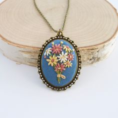 "This embroidered daisy necklace is so darling! Make a statement with this gorgeous vintage inspired hand embroidered necklace stitched on a blue background. Multicolored daisies are the showstoppers on this beauty! Whether you are looking for a classic piece, or something with sentiment , this piece will certainly do the trick! This handmade necklace would make a perfect gift for anyone you love! I'll string this pendant on a custom length chain. (see chart in listing pictures) This little darl Handmade Blue Necklaces For Spring, Handmade Vintage Necklaces For Spring, Blue Flower Necklace, Hand Embroidered Necklace, Decoupage Jars, Daisy Bouquet, Light Sky Blue, Embroidered Necklace, Daisy Necklace