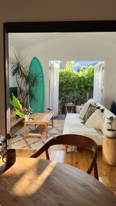 a living room filled with furniture and a surfboard in the back door window sill