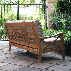 a wooden chair sitting on top of a brick floor next to a plant filled area