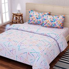 a bed with colorful sheets and pillows on top of it