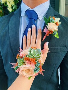 a man in a suit and tie with flowers on his wrist holding another mans hand