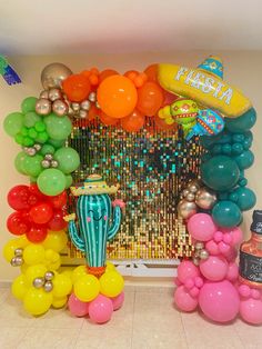 balloons and confetti are arranged on the floor in front of a party backdrop