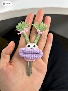 a hand holding a crocheted keychain with an eyeball on it